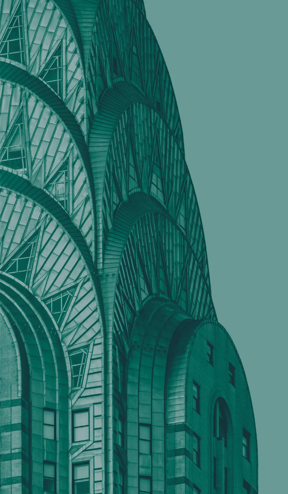 The crown of the Chrysler Building, its stacked steel arches and triangular windows rising against a plain sky.